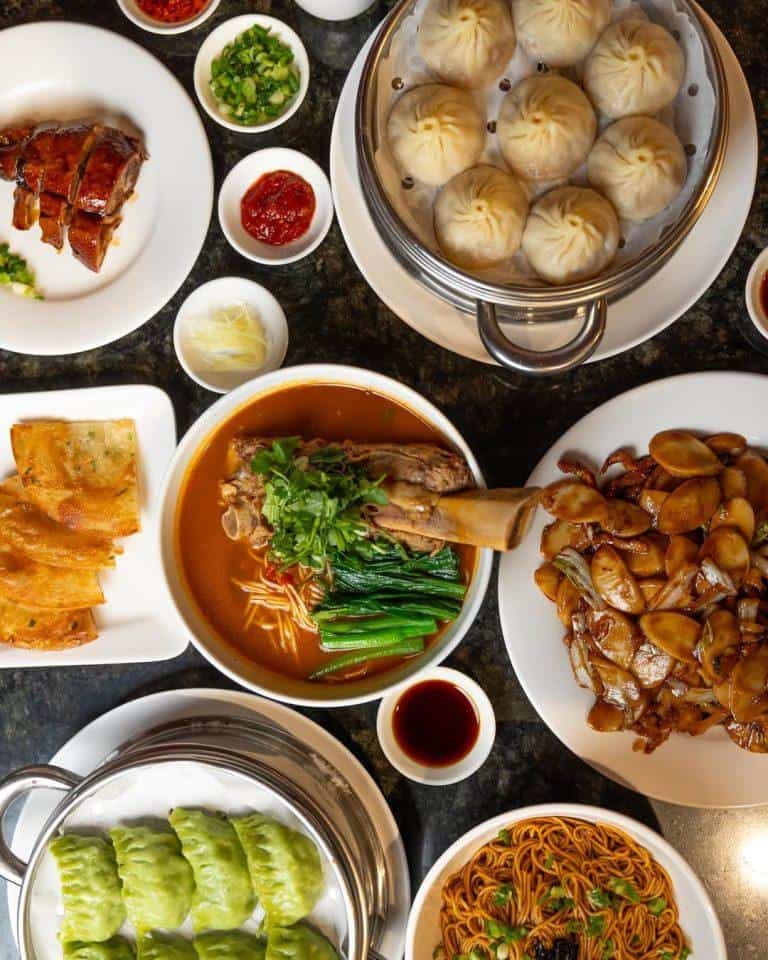 Steamed dumplings with dipping sauces, savory noodles, roasted meats, and fresh vegetables, showcasing authentic Chinatown cuisine. Perfect for food lovers exploring Asian culinary delights.